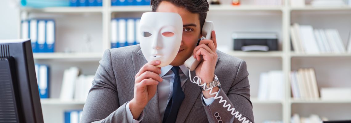 Man with mask in hand talking on phone