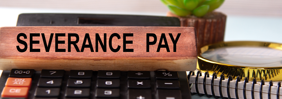 SEVERANCE PAY - words on a wooden block with a calculator in the background