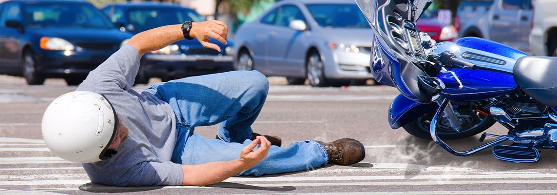 Man sliding in road along with motorcycle after accident