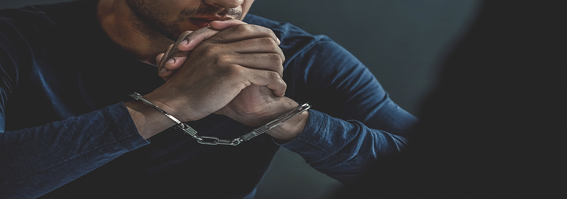 Criminal man with handcuffs in interrogation room