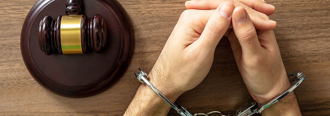 Gavel and handcuffed hands-on table