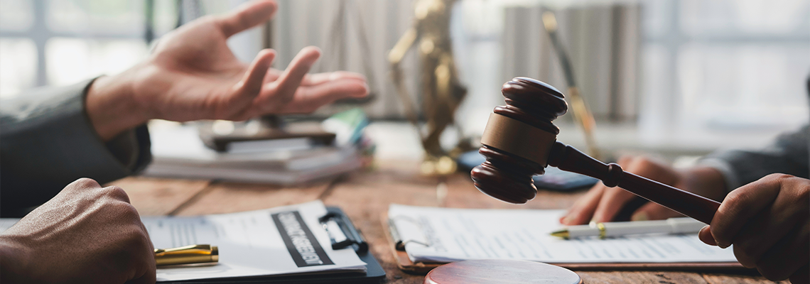 Judge holding a gavel while presiding over a legal discussion among lawyers