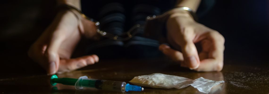 Handcuffed man with drug pouch Infront of him