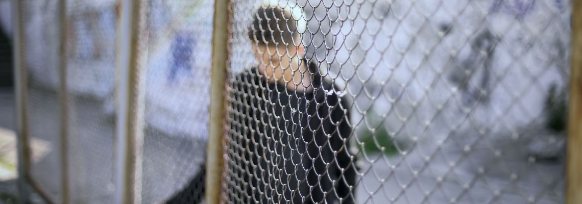 Teen boy behind fence confinement