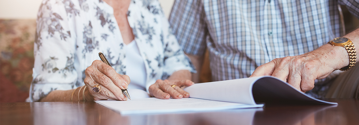 Senior woman signing documents with her husband