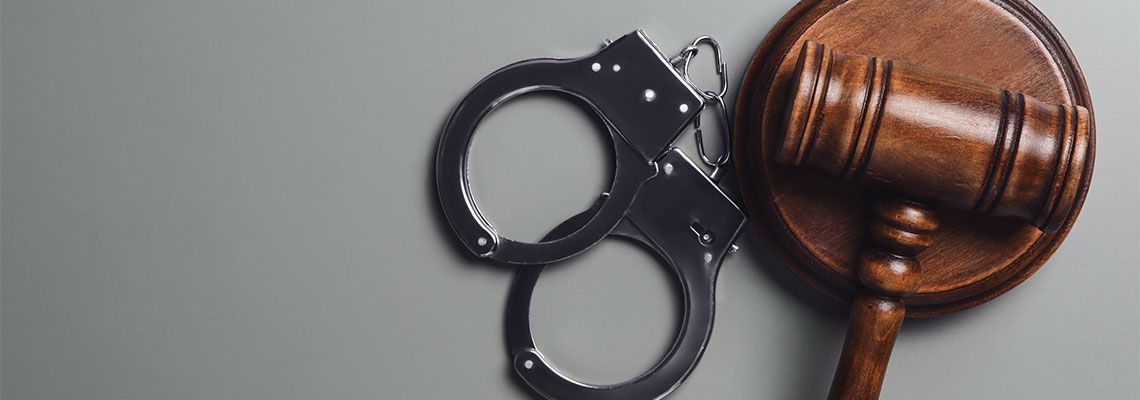 Judge's gavel and handcuffs on grey background