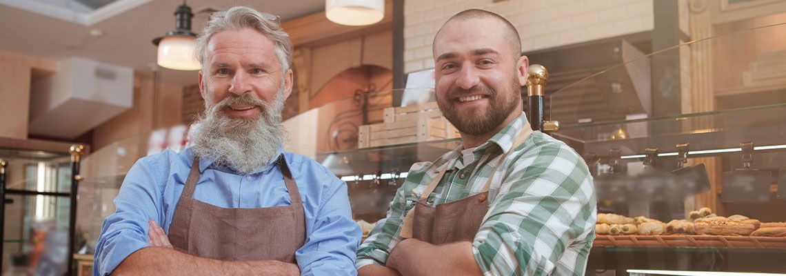 Cheerful father and son bakers enjoying working at their bakery