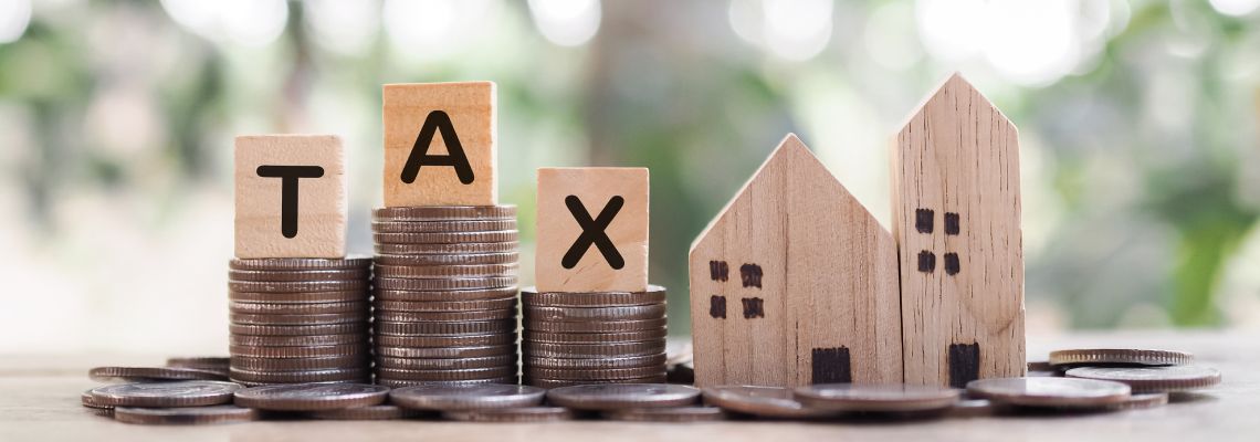 Miniature house and wooden block forming word tax