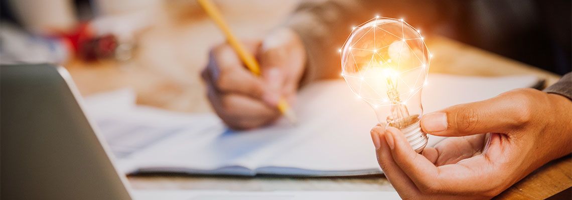 Man holding light bulb in hand and noting down ideas