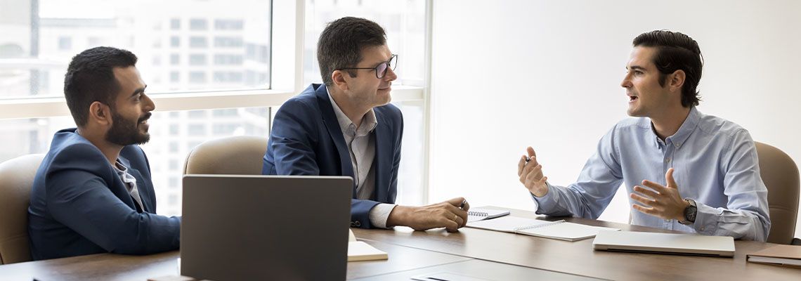 Three shareholders engaged in discussion seated at conference table