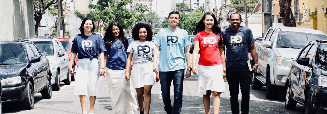 group of people wearing the same shirt walking down the street
