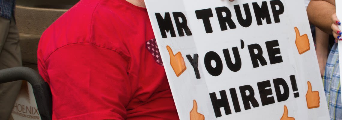 Man holding sign that says "you're hired"