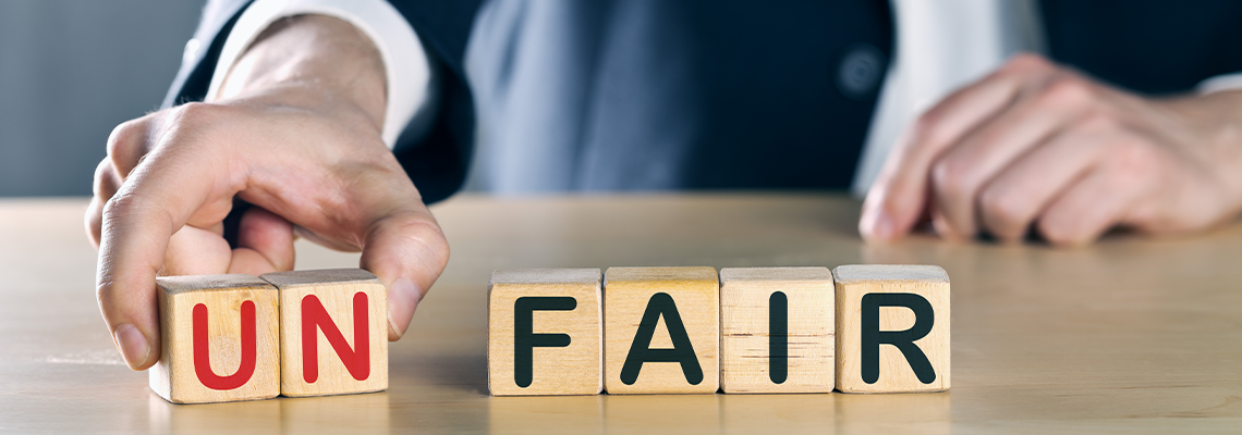 Attorney taking the "UN" out of "Unfair" spelled in wooden blocks