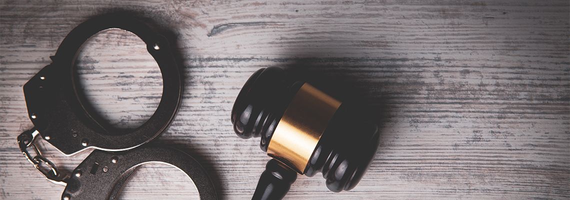 Gavel and handcuff on wooden table