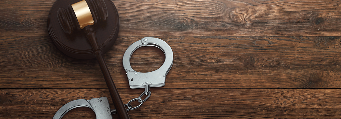 Judge's gavel and handcuffs on wooden background