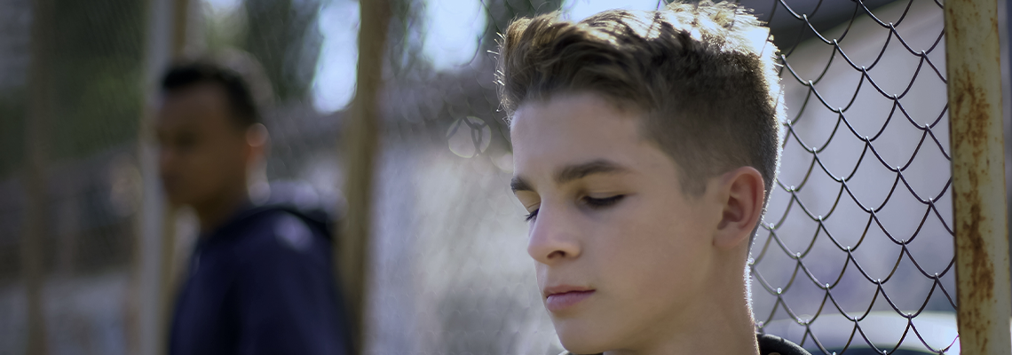 Teenage Boys Leaning on Metal Fence