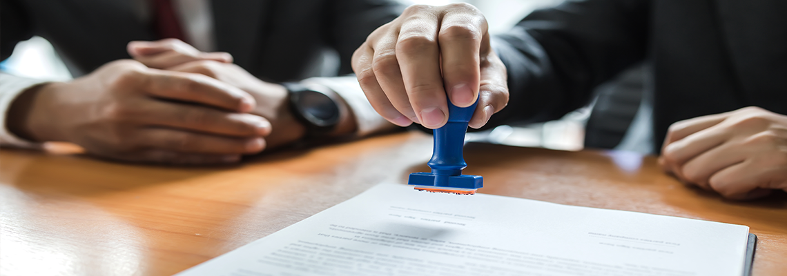Man in suit stamping with approved stamp on document.