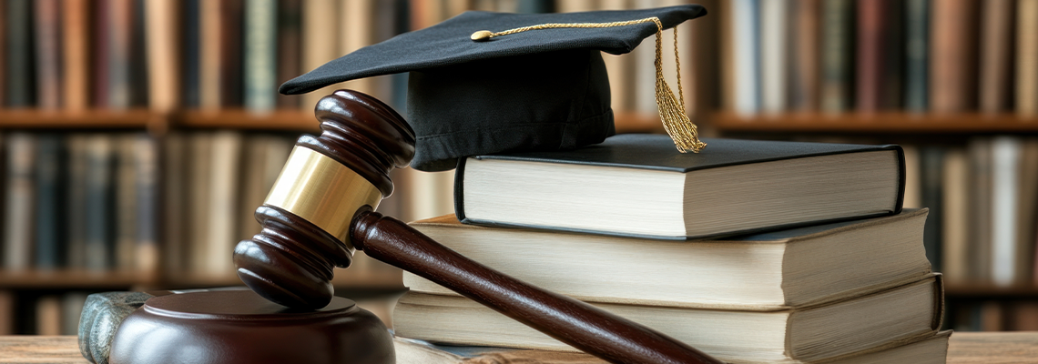 Graduation hat sitting on law books with gavel in library