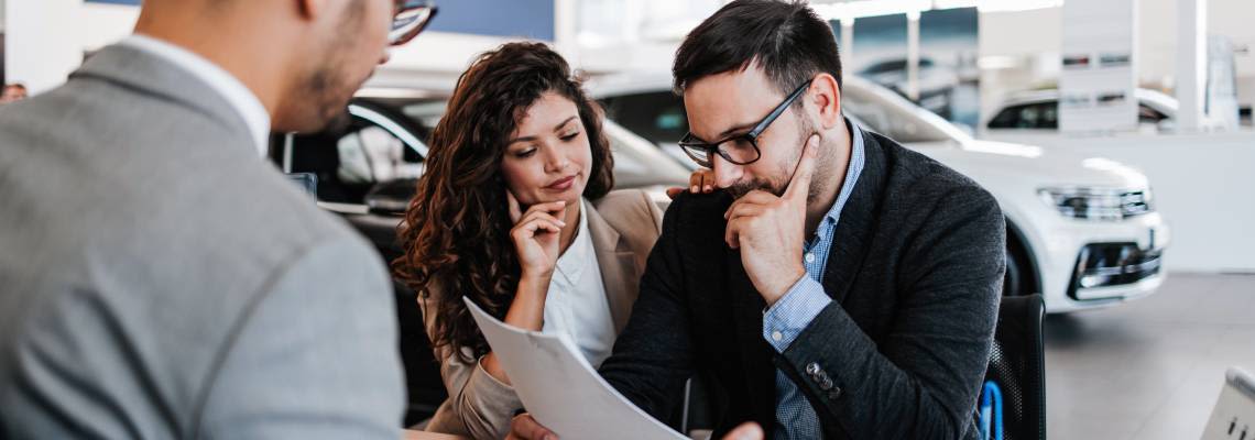 Man examining document carefully at a car dealership