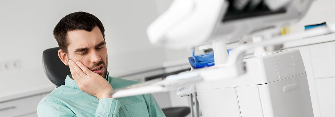 Male suffering from tooth pain sitting in dental clinic