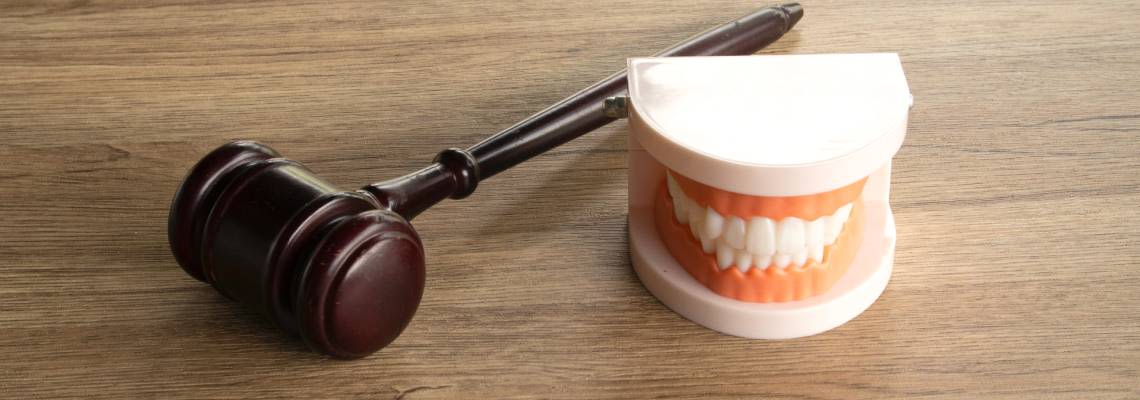 Legal gavel positioned next to a dental teeth model