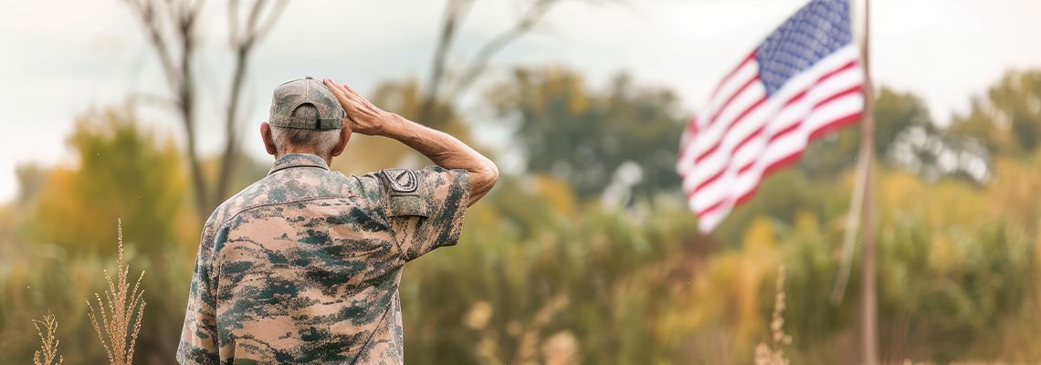 A soldier saluting in a field with an American flag