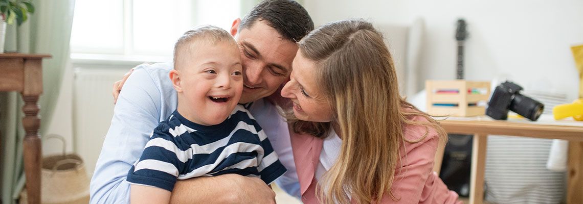 Cheerful down syndrome boy with parents indoors