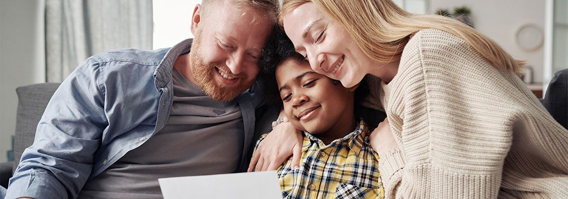 Parents embracing adopted son while reading adoption agreement paper
