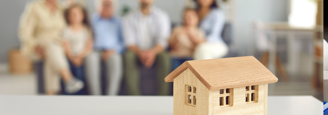 Small little toy house on table against blurred background with whole big family