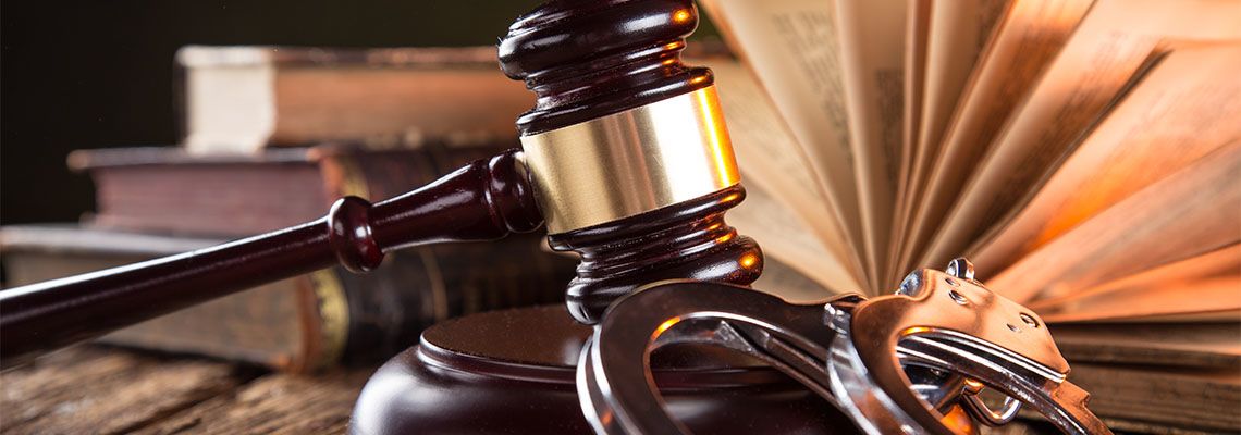 Wooden gavel, handcuff and books on wooden table
