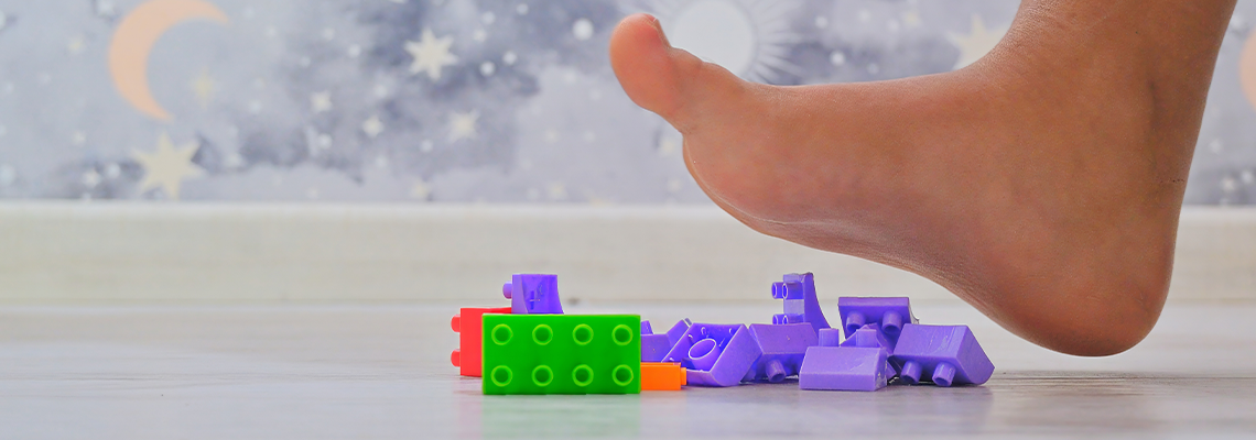 A kid foot hovers over toy building blocks