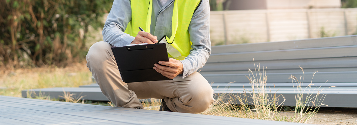 Asian inspector checking structure of new property and taking note