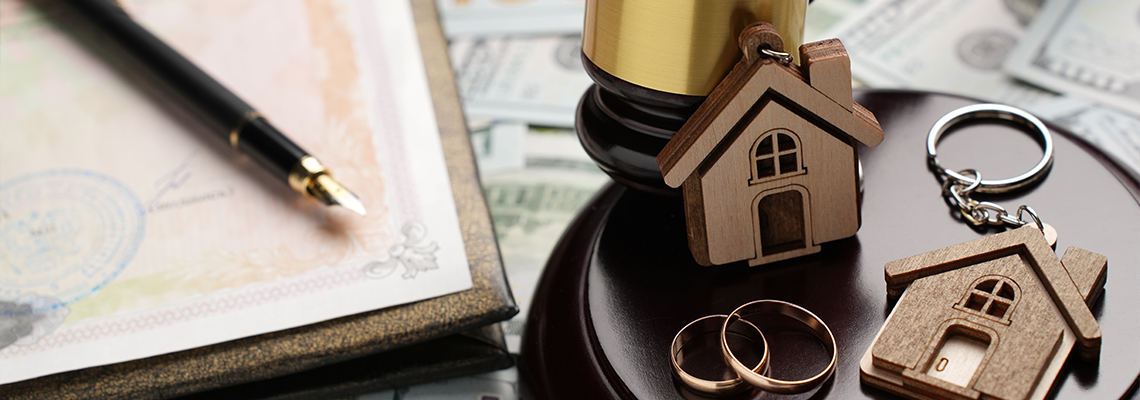 Property Division in Divorce and Marital Law Concept. Gold wedding rings, wooden house model