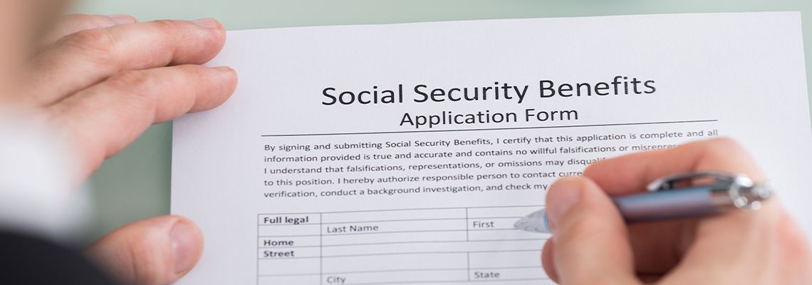 Person Hand Filling Social Security Benefits Form
