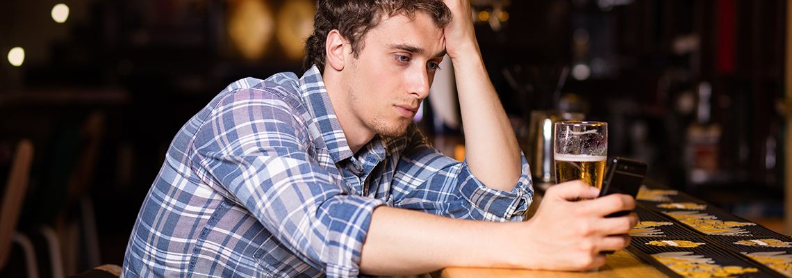Person sitting at bar looking at cell phone