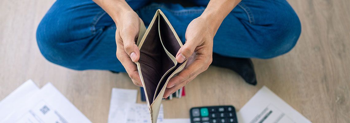 Man looking at empty wallet while calculating due bills