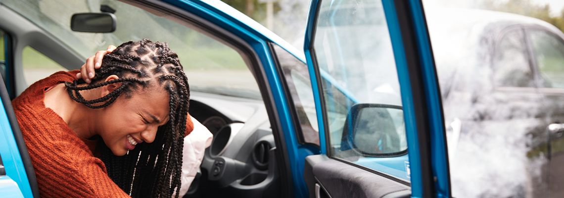 Women with whiplash injury getting out of car after accident