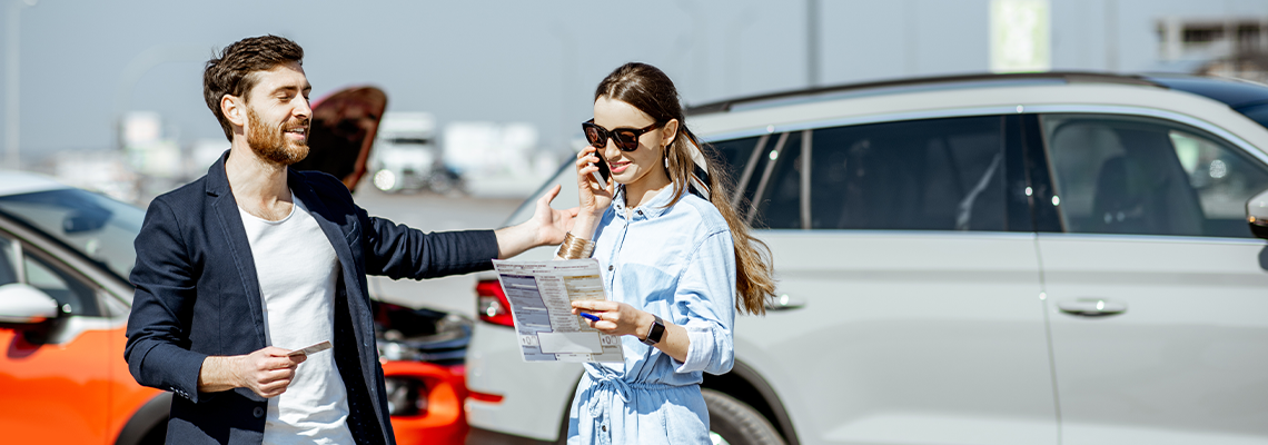 Man and woman arguing, standing together on the road with their cars