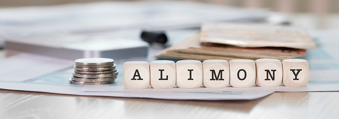 Word ALIMONY composed of wooden letters and coins on table