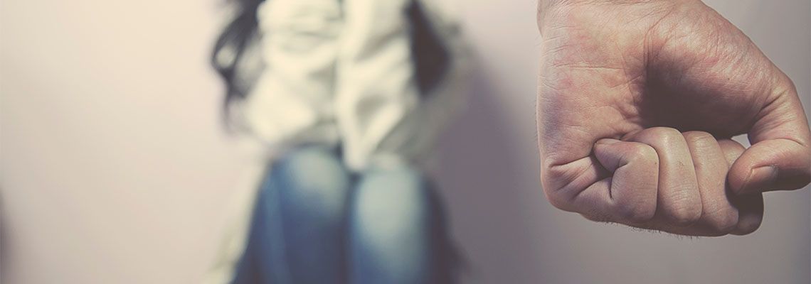 Closed fist of man with scared women in background