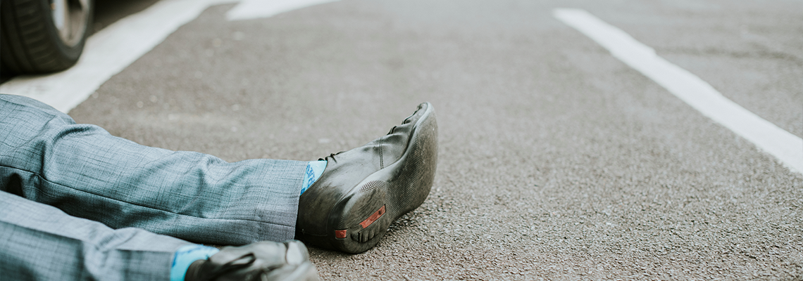 Person lying on the ground after a car accident