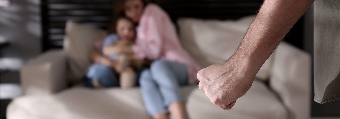Man with tight fist and scared family in background