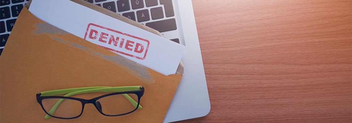 Document with denied stamp put on laptop