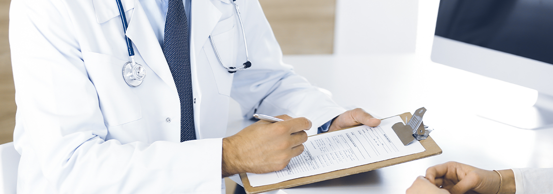 Doctor and patient discussing medical exam results while sitting at the desk in clinic