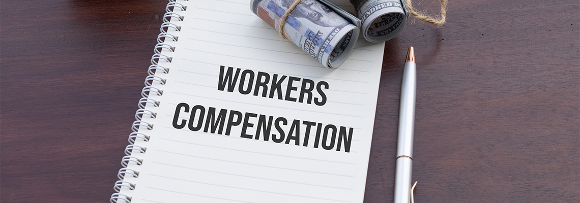 A notebook labeled 'Workers Compensation' accompanied by cash