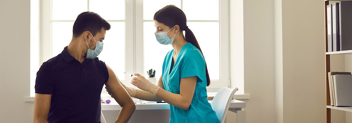 Female Nurse giving Flu shot to young man