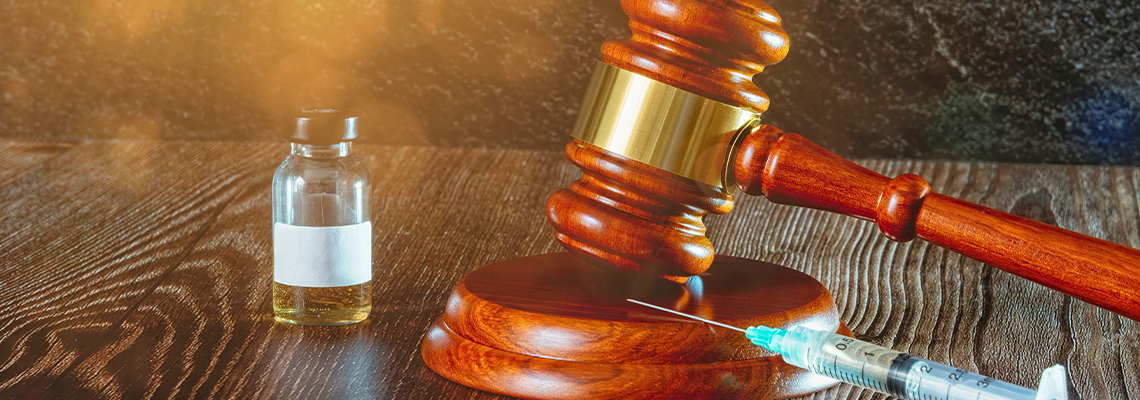 Judges hammer, syringe and vaccine bottle on a wooden background with sun light