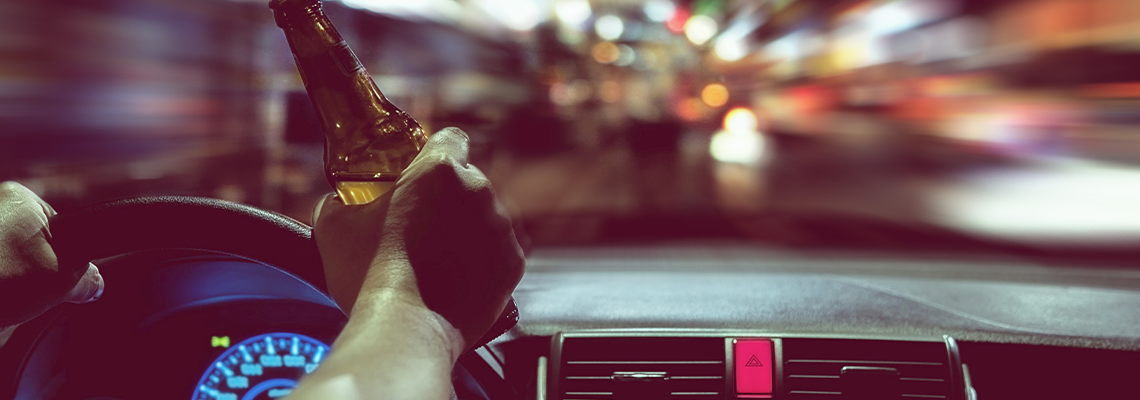 Man drink beer while driving at night in the city dangerously
