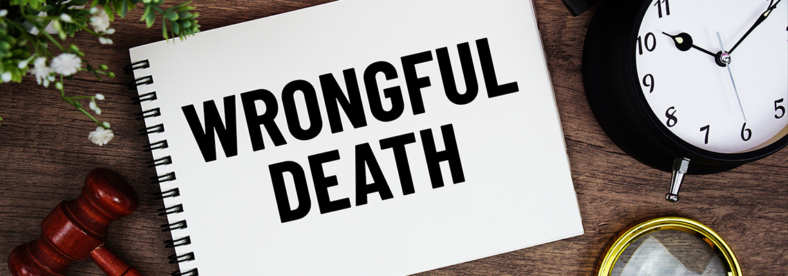 Wrongful Death message written on notepad with alarm clock, wood gavel