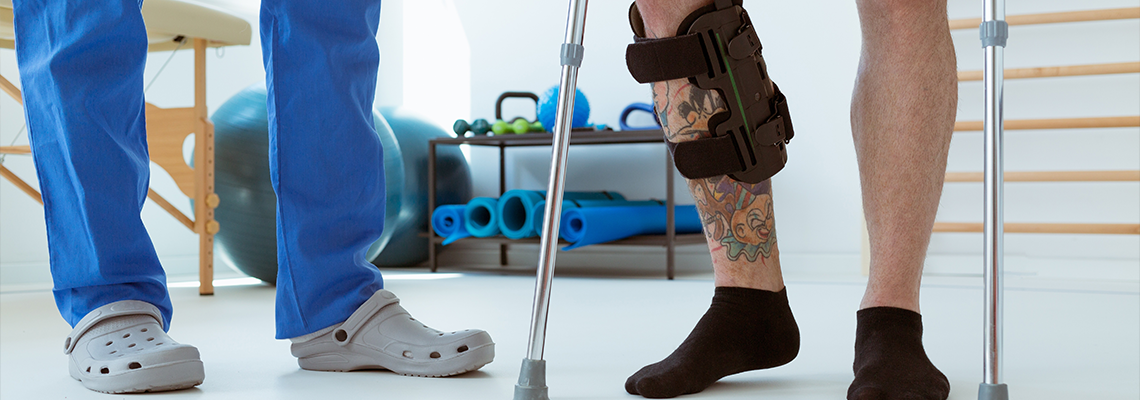 Man after car accident in an orthosis and on crutches learning to walk in the clinic